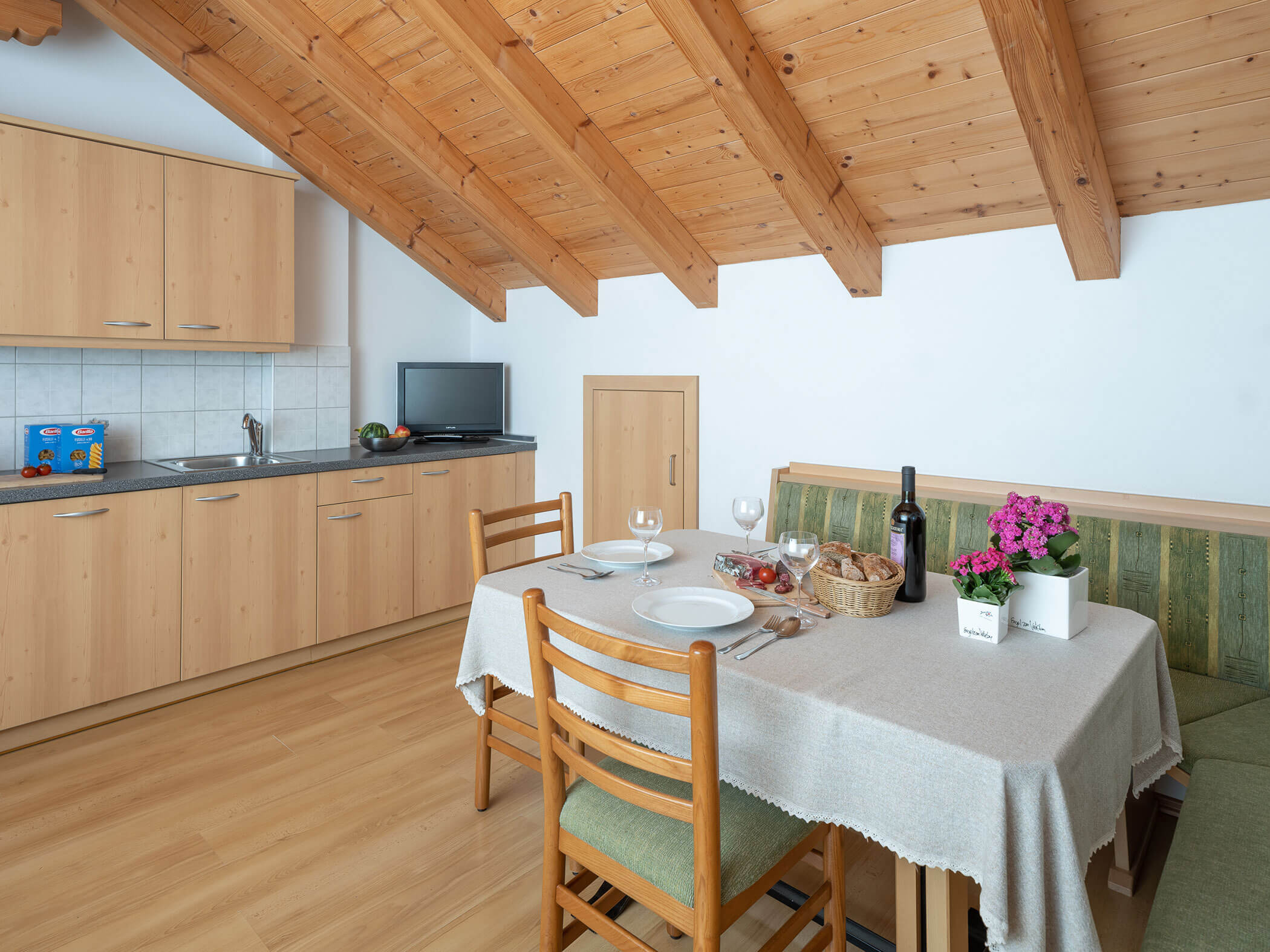 Gedeckter Esstisch mit einer Flasche Wein, Speck und Brot im Apartment Wildgall - Branterhof