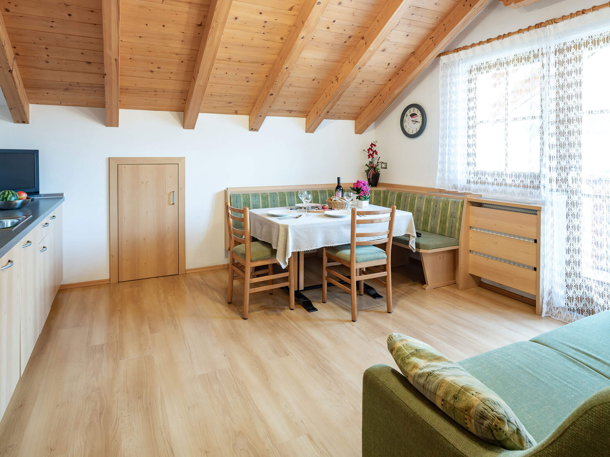 Wohn-Esszimmer mit Esstisch, Fernseher und grünem Sofa im Apartment Wildgall - Branterhof