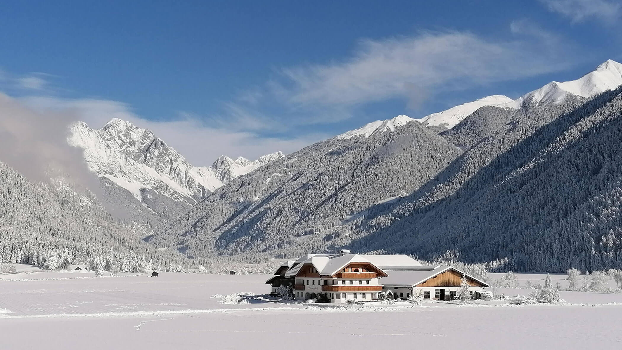 The Branterhof from the outside in winter with snow-covered mountains in the background
